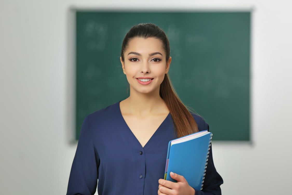 Teacher with Notebook in Classroom